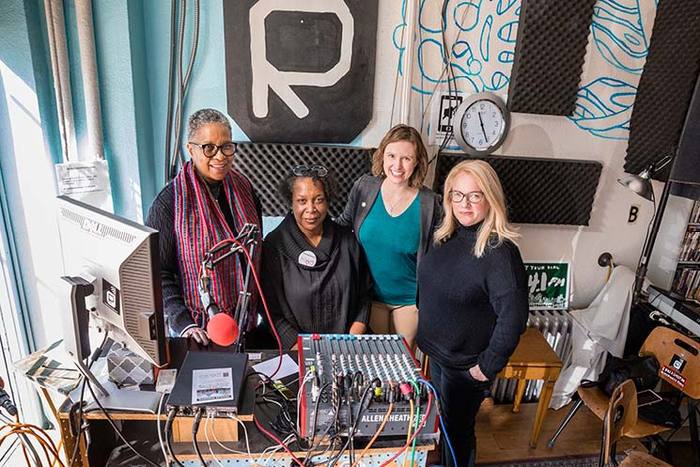 Four women standing in front of sound equipment